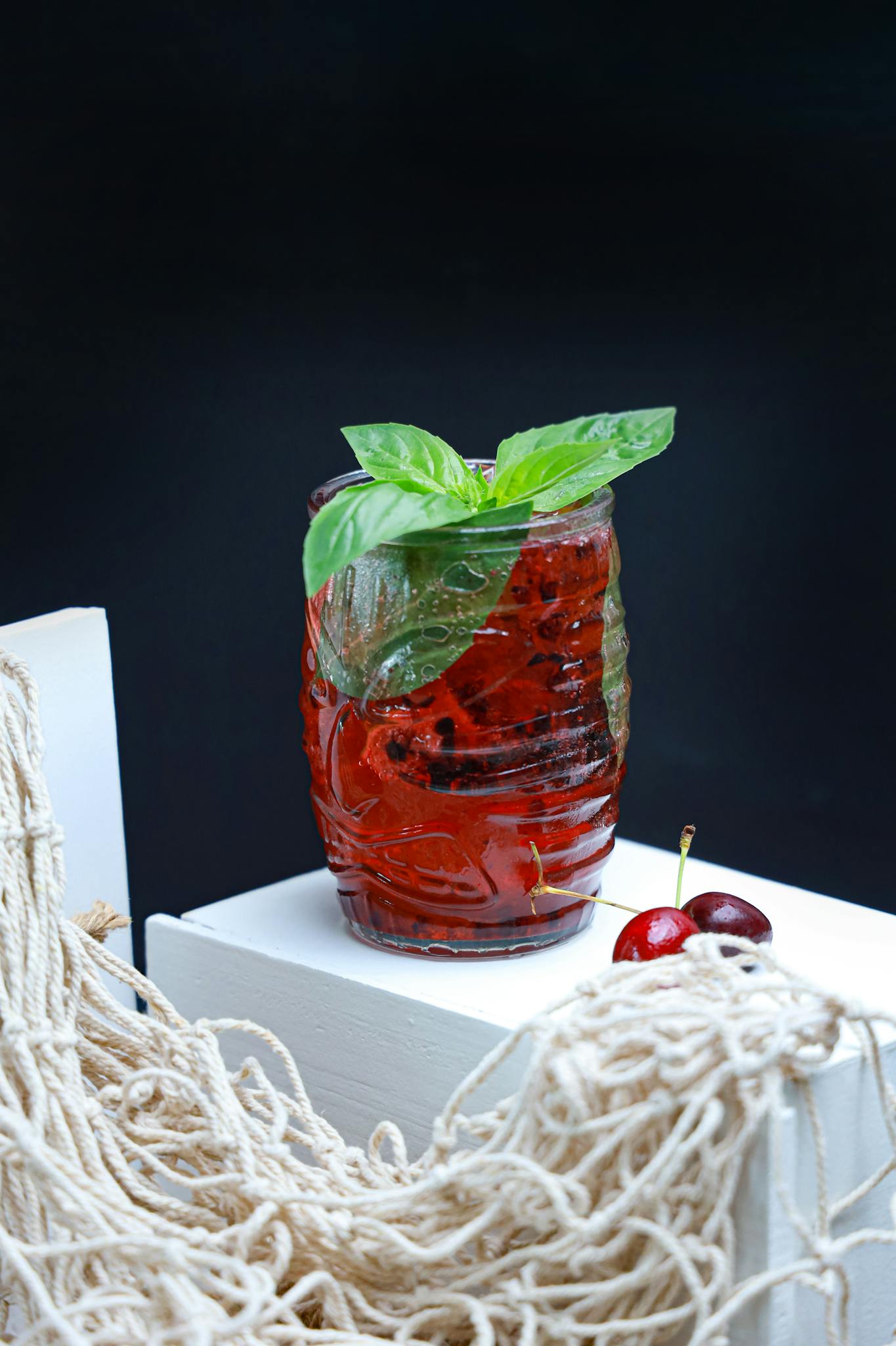 A cool cherry and basil infused drink with mint garnish, perfect for summer refreshment.