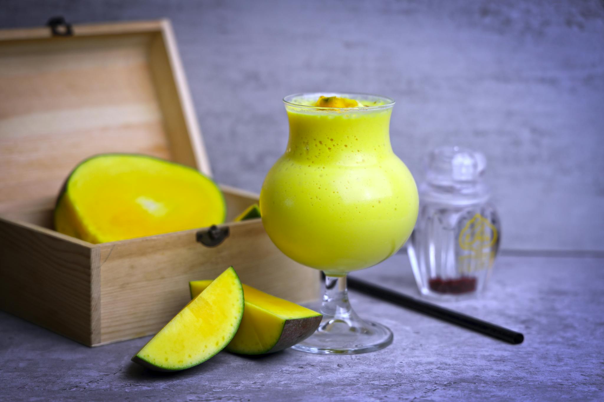 A vibrant glass of mango juice paired with fresh mango slices, perfect for a healthy refreshment.