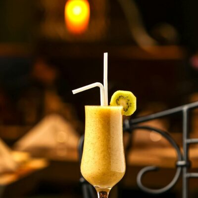 Delicious tropical fruit smoothie with kiwi slice served in a tall glass, perfect for summer refreshment.