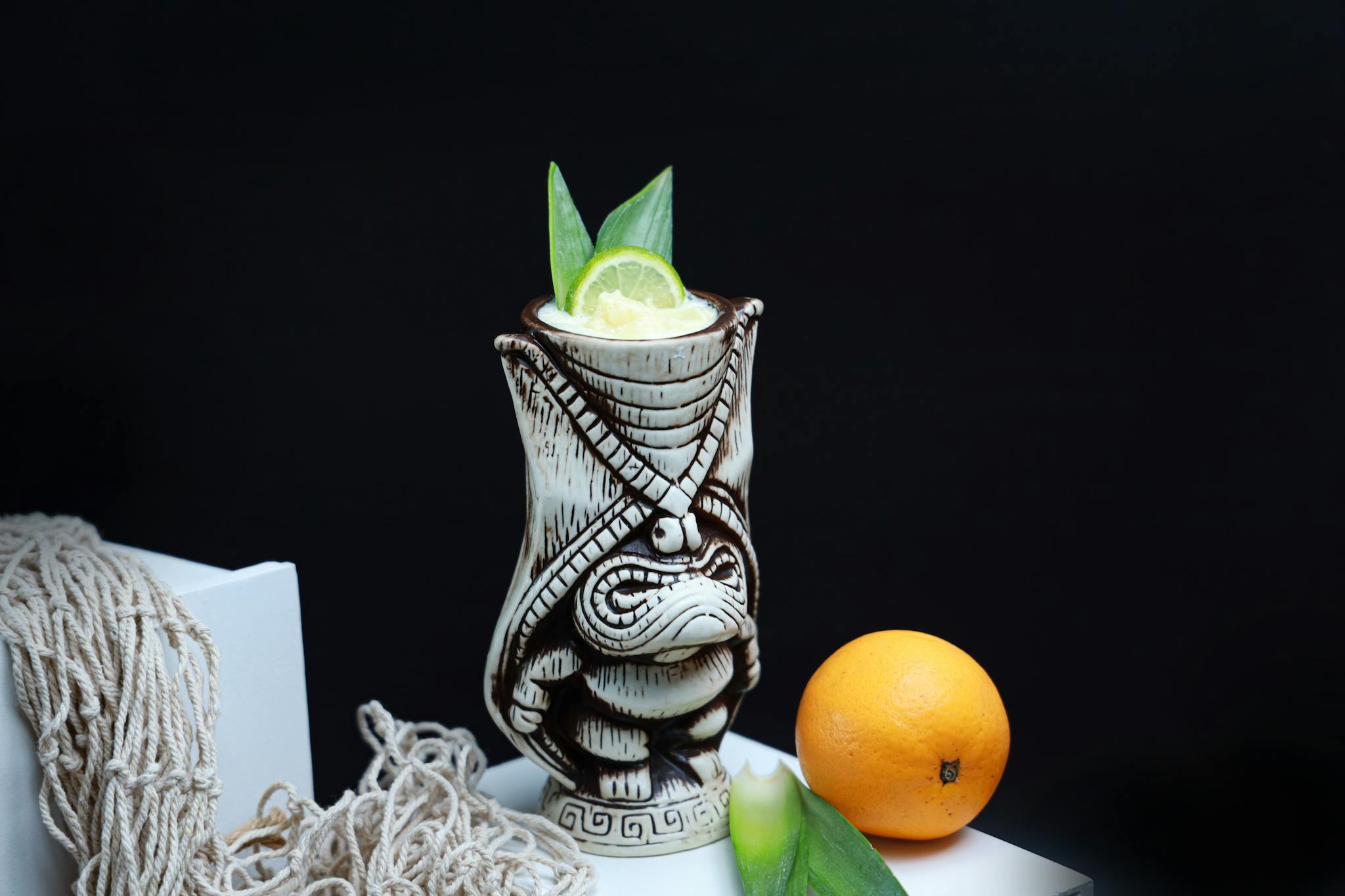Fresh tropical citrus drink served in a tiki mug with lime garnish on a dark background.