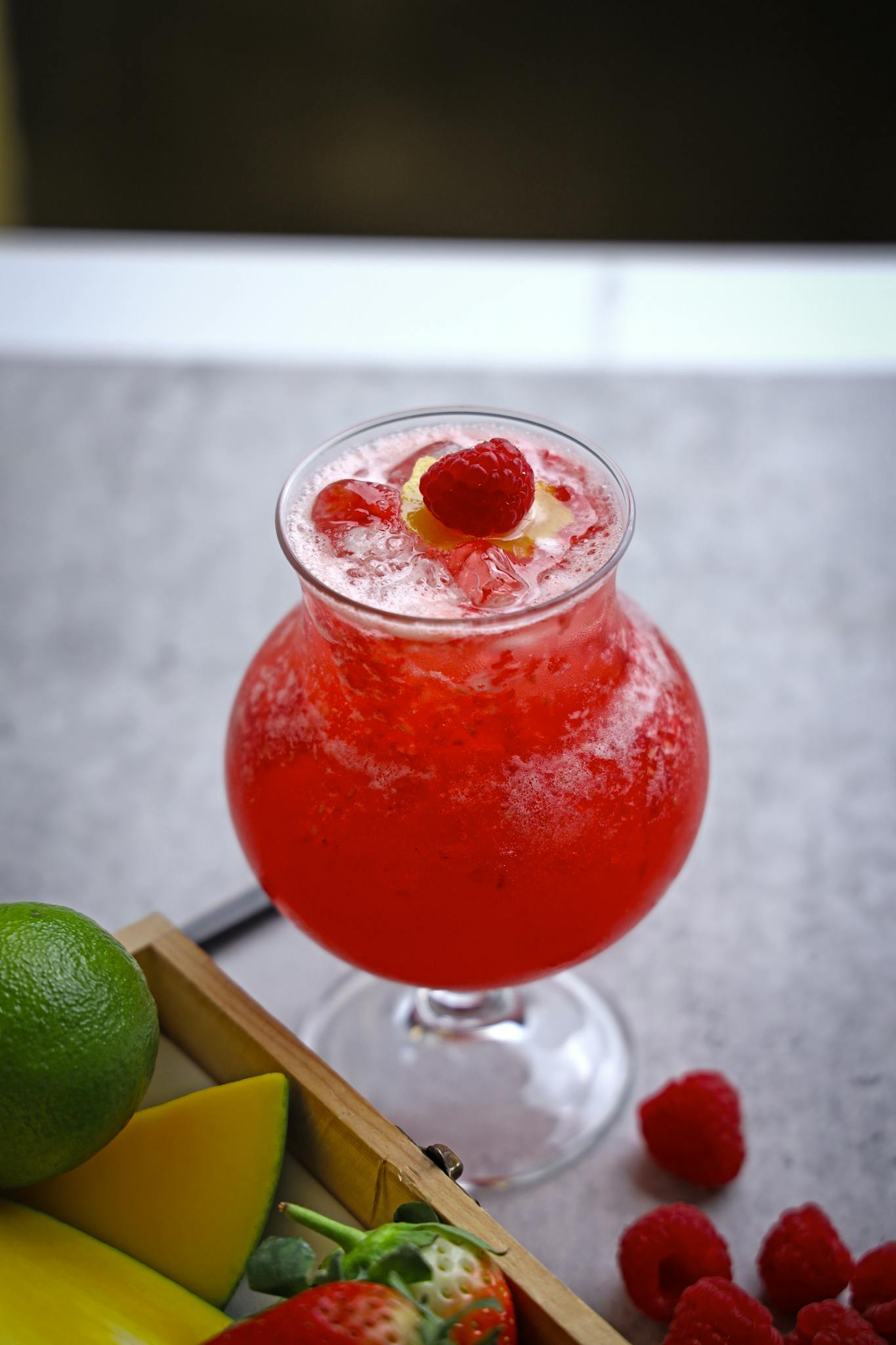 Vibrant raspberry lemonade surrounded by fresh fruits, perfect for summer refreshment.